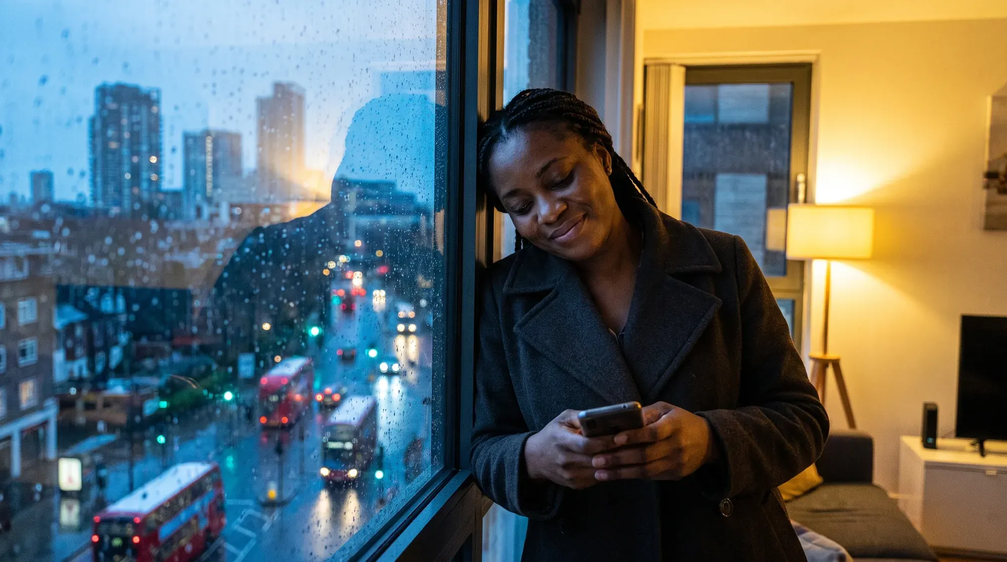 A daughter in a dusk-lit kitchen abroad smiles at her phone, then a sunlit Owerri veranda where a caregiver and her father wave at the camera.