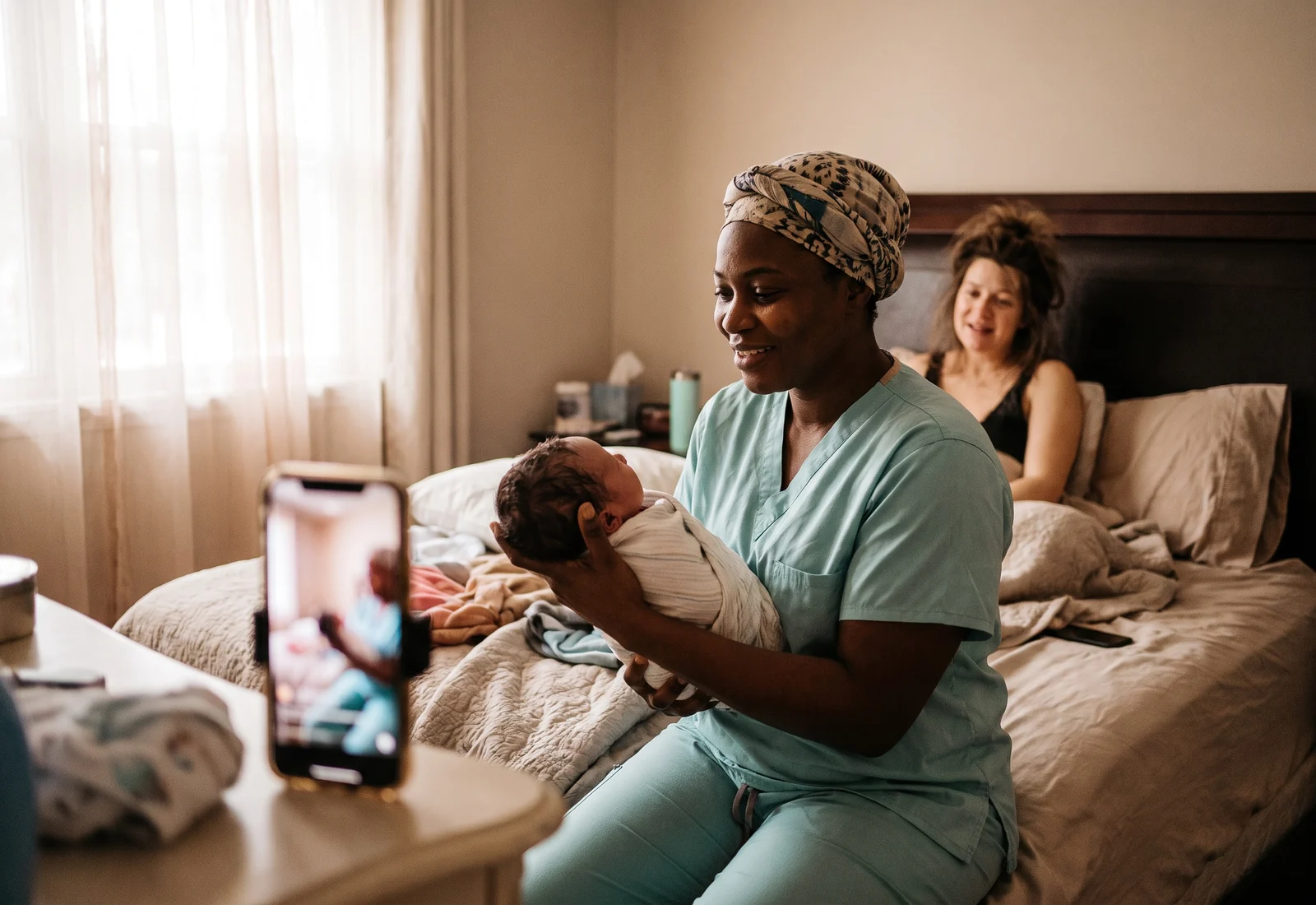 A new grandmother abroad meets the baby on a video call as the caregiver holds the newborn up to the camera.