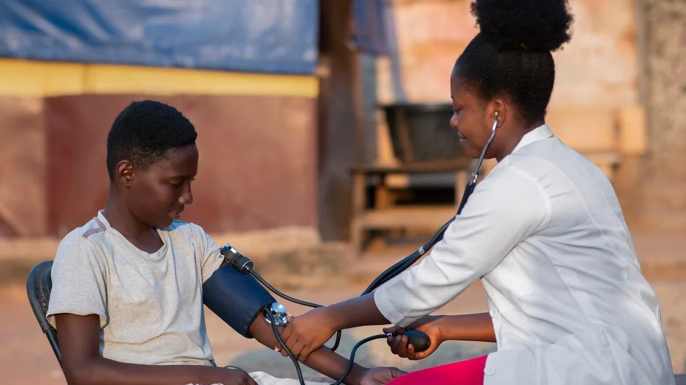 An Insyt health worker in a white coat runs an on-site blood pressure screening for a young man.